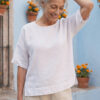 Mujer vistiendo blusa manga amplia de lino blanca y pantalon color avena