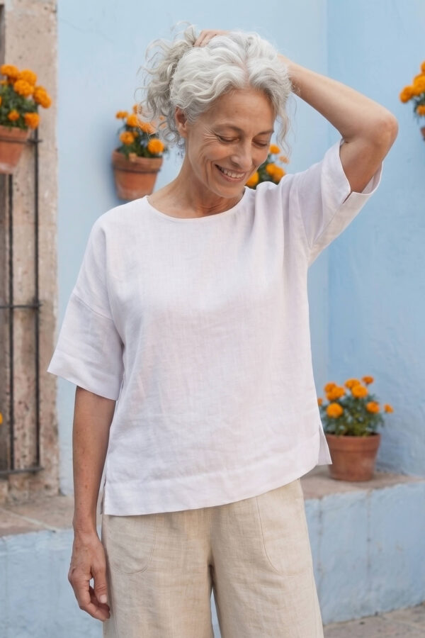 Mujer vistiendo blusa manga amplia de lino blanca y pantalon color avena