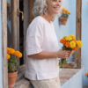 Mujer vistiendo blusa manga amplia de lino blanca y pantalon color avena
