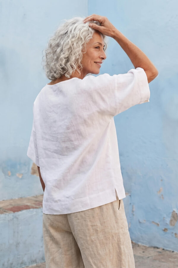 Mujer vistiendo blusa manga amplia de lino blanca y pantalon color avena