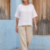 Mujer vistiendo blusa manga amplia de lino blanca y pantalon color avena