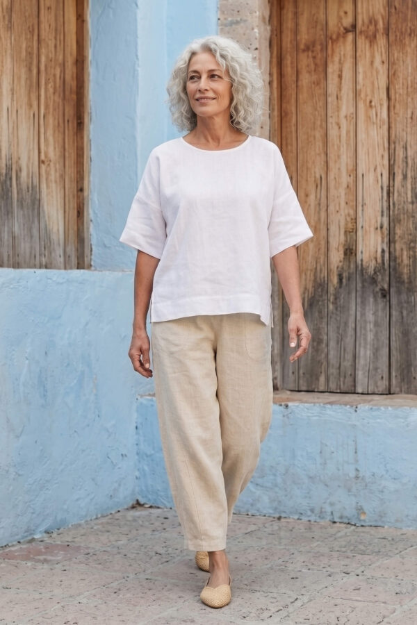 Mujer vistiendo blusa manga amplia de lino blanca y pantalon color avena