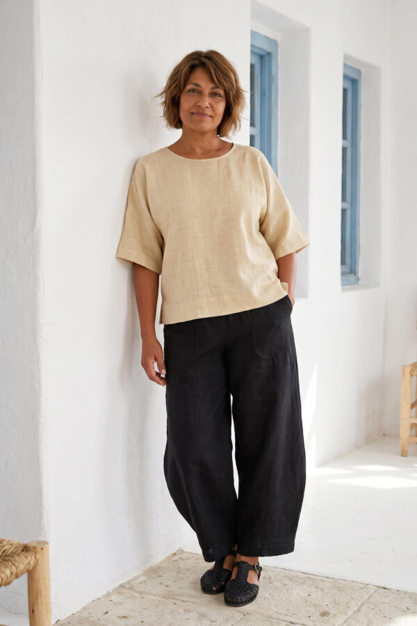 Mujer vistiendo blusa manga amplia de lino color paja y pantalon negro