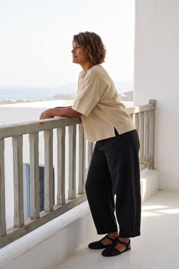 Mujer vistiendo blusa manga amplia de lino color paja y pantalon negro