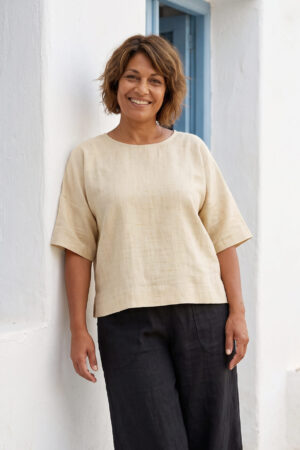 Mujer vistiendo blusa manga amplia de lino color paja y pantalon negro