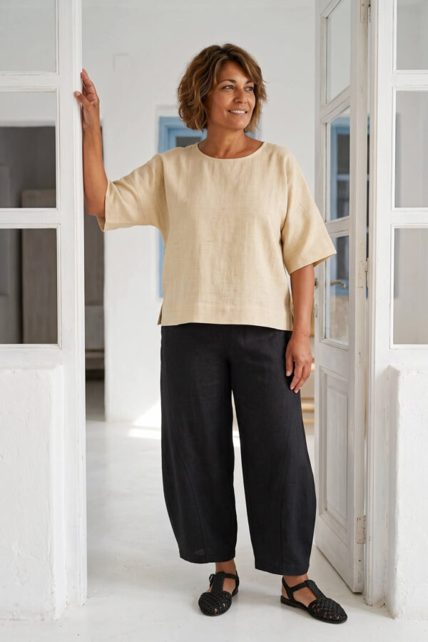 Mujer vistiendo blusa manga amplia de lino color paja y pantalon negro