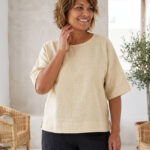 Mujer vistiendo blusa manga amplia de lino color paja y pantalon negro