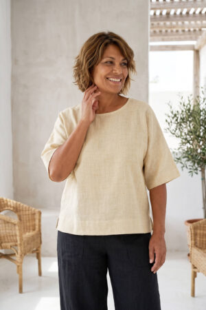 Mujer vistiendo blusa manga amplia de lino color paja y pantalon negro