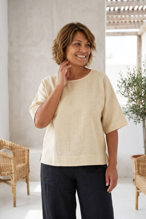 Mujer vistiendo blusa manga amplia de lino color paja y pantalon negro