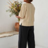Mujer vistiendo blusa manga amplia de lino color paja y pantalon negro