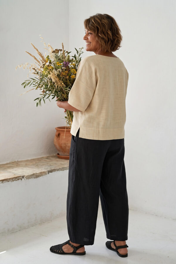 Mujer vistiendo blusa manga amplia de lino color paja y pantalon negro