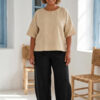 Mujer vistiendo blusa manga amplia de lino color paja y pantalon negro